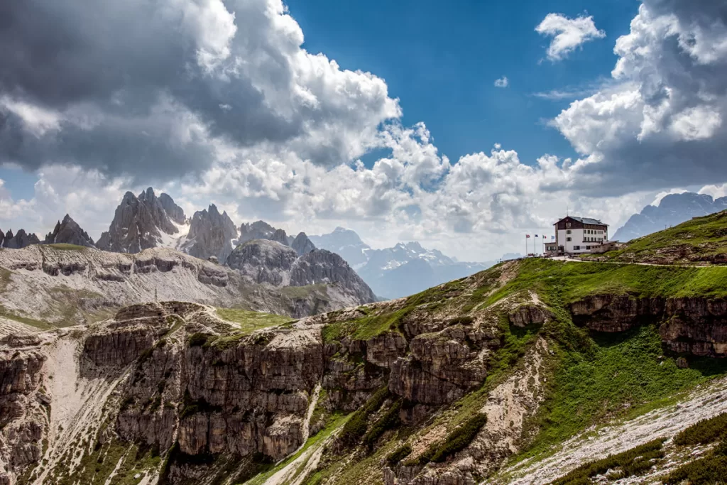 Rifugio Auronzo stands high on a grassy ridge overlooking the Tre Cime di Lavaredo, one of the most famous Dolomites photo spots.