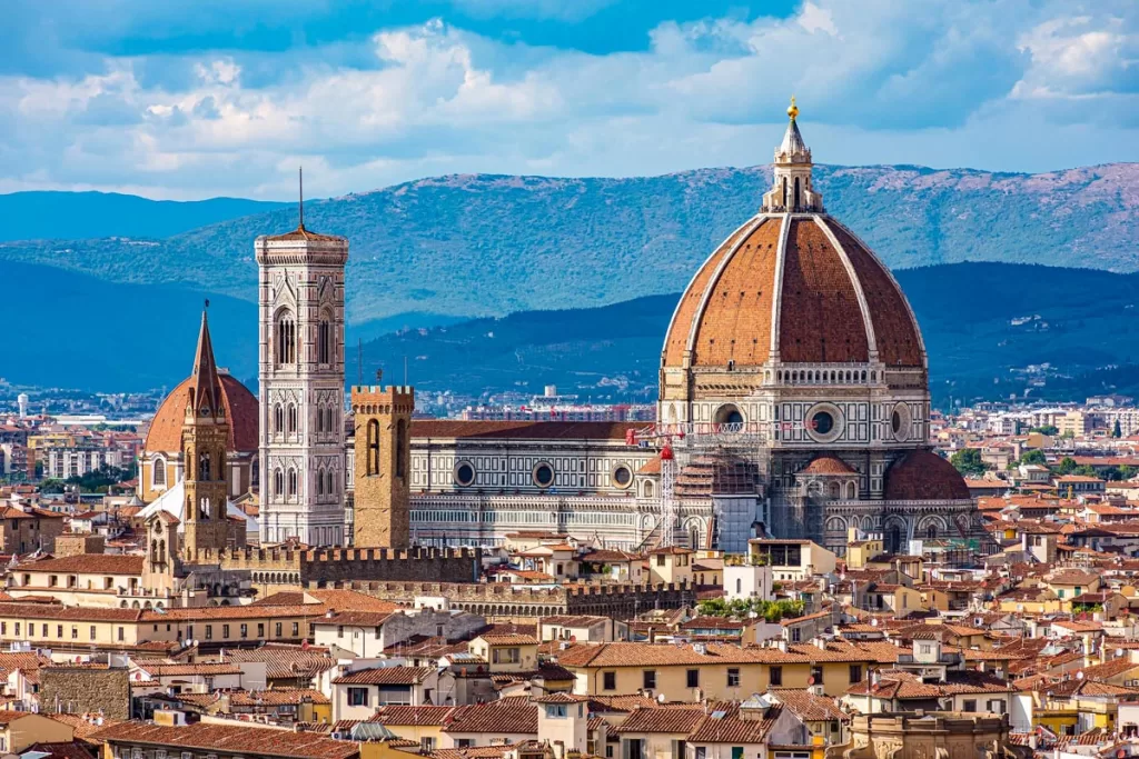 The iconic dome and bell tower of Santa Maria del Fiore rise above the terracotta roofs of Florence, Italy.