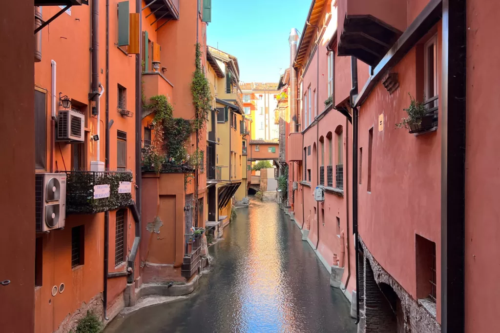 La Finestrella, a popular photo spot in Bologna, Italy, peeks through a small window to view a medieval canal flanked by brightly-painted homes.