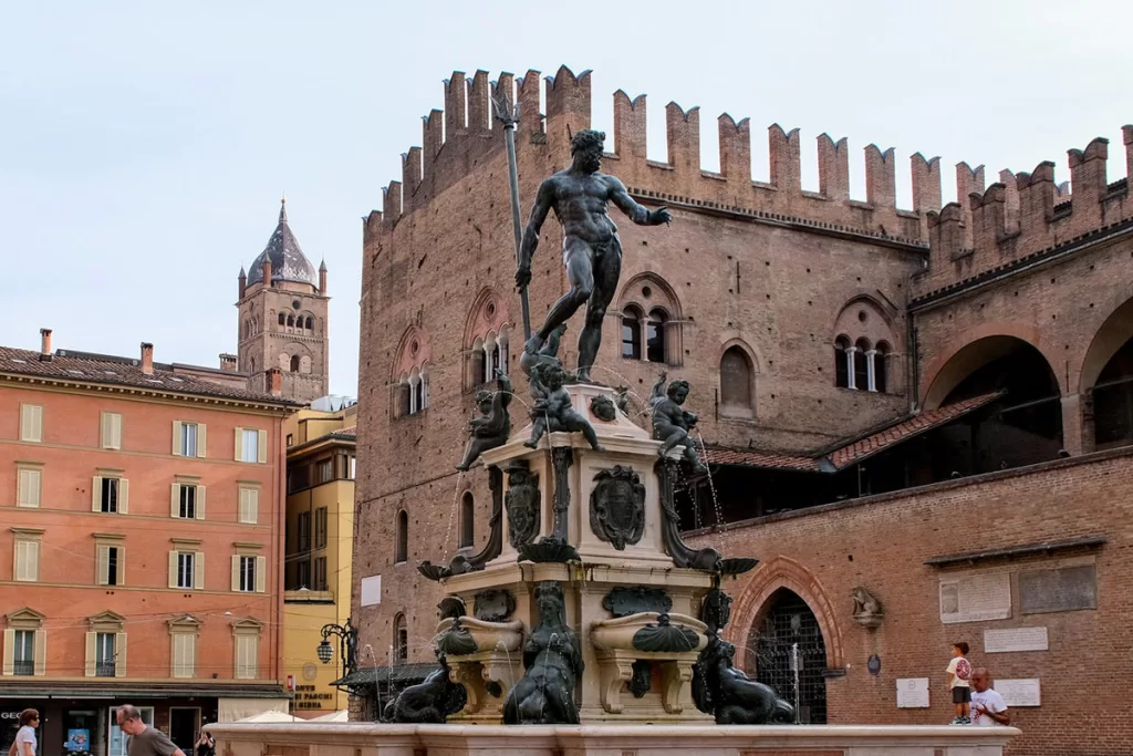 The iconic Neptune Fountain stands against medieval brick buildings in Bologna, Italy.