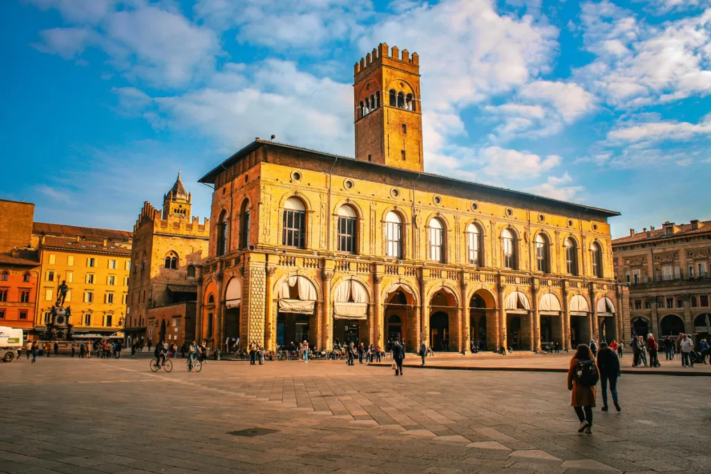 Pedestrians walk through Piazza Maggiore in Bologna, Italy.