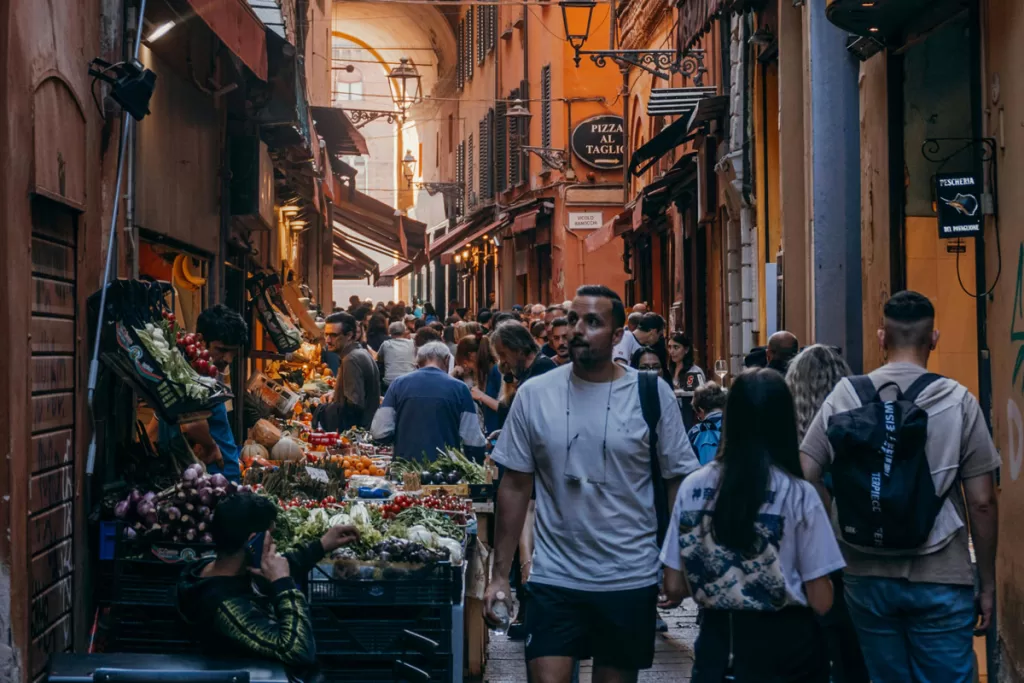Tourists stroll the crowded, narrow pedestrian streets of Bologna's Quadrilatero market district.