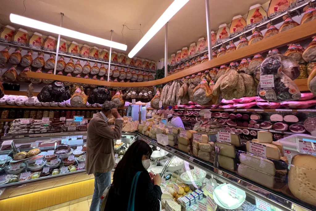 Shoppers peruse local meats and cheeses at a salumeria in Bologna, Italy's medieval Quadrilatero food market.