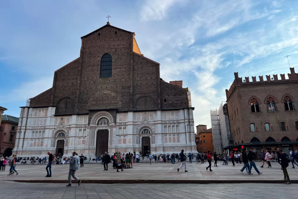 Pedestrians cross Piazza Maggiore in front of the Basilica di San Petronio in Bologna, Italy. Touring the Basilica is one of the most popular things to do in Bologna.