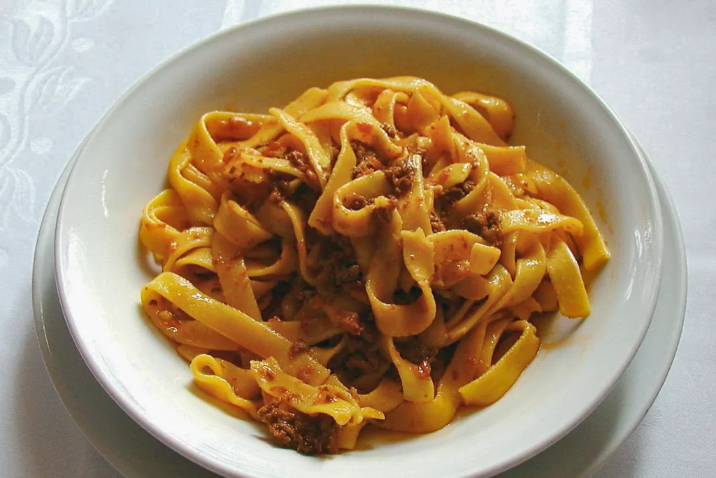 A close-up of a bowl filled with tagliatelle bolognese pasta.