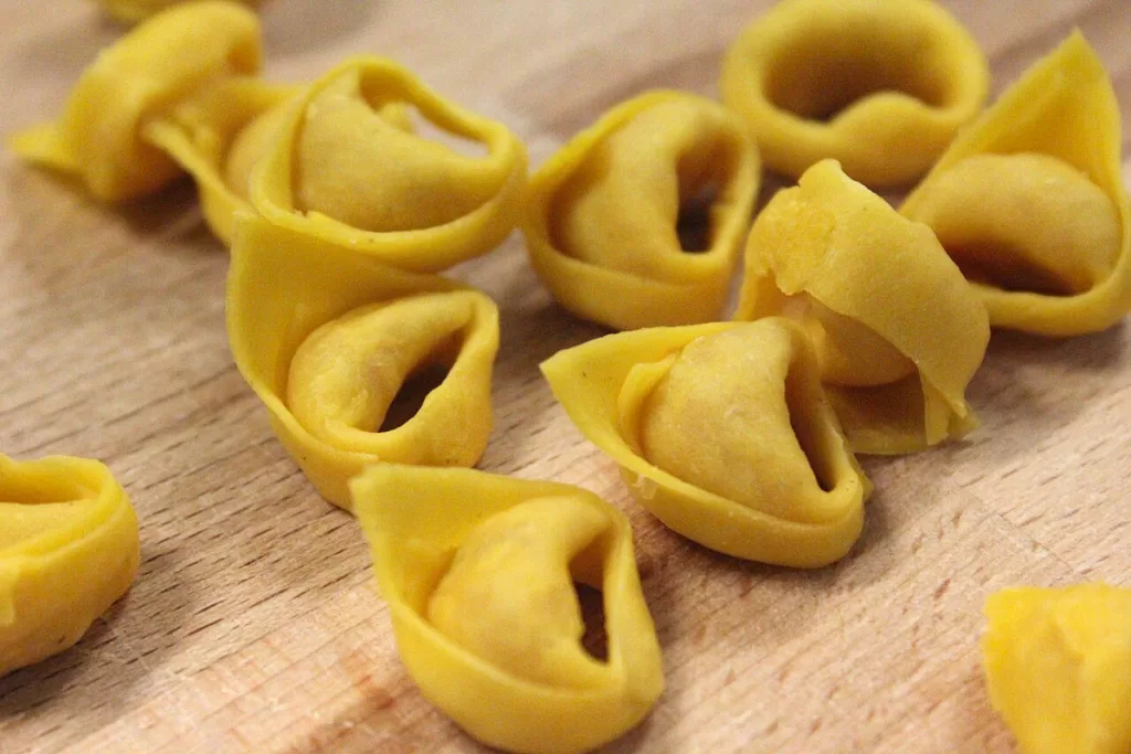 A close-up of stuffed tortellini pasta on a wooden table.