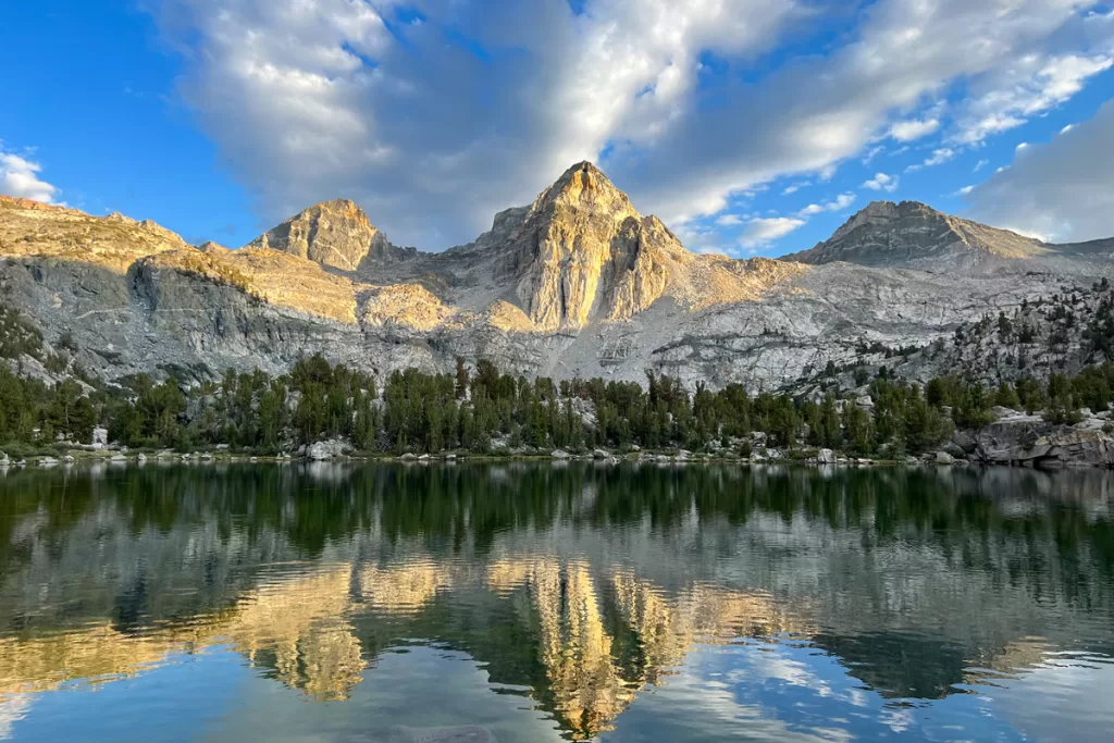 Granite peaks and a forested shoreline are reflected in the waters of Middle Rae Lake in Kings Canyon National Park.