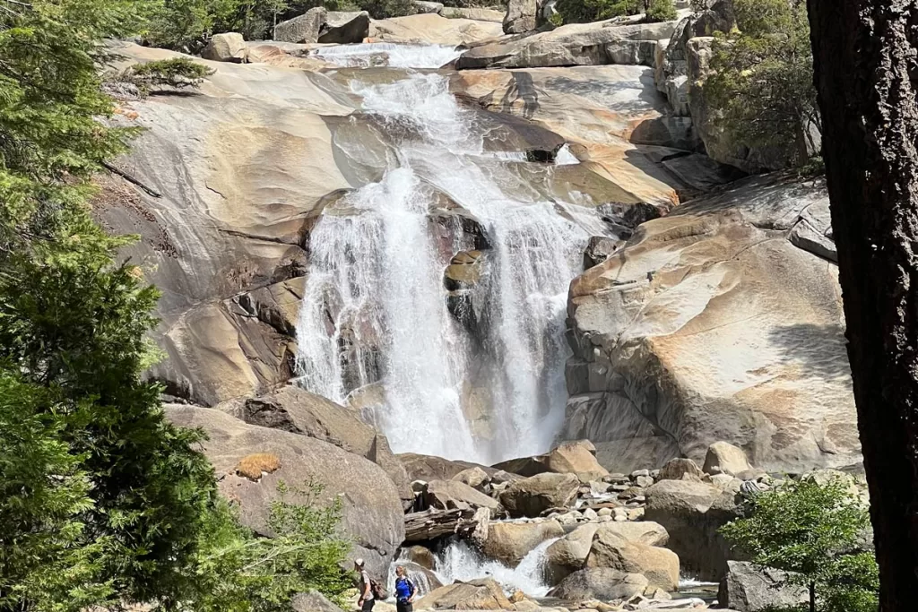 Two hikers stand at the base of Mist Falls in Kings Canyon National Park.