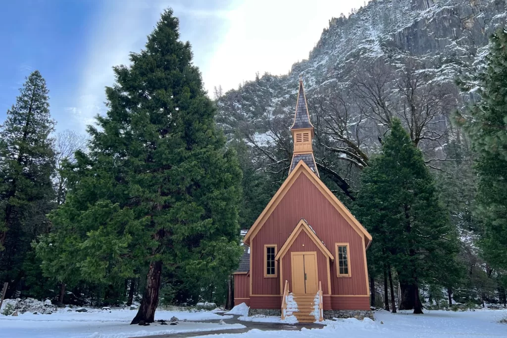 Yosemite Valley Chapel on a sunny winter day, surrounded by snow in Yosemite National Park.