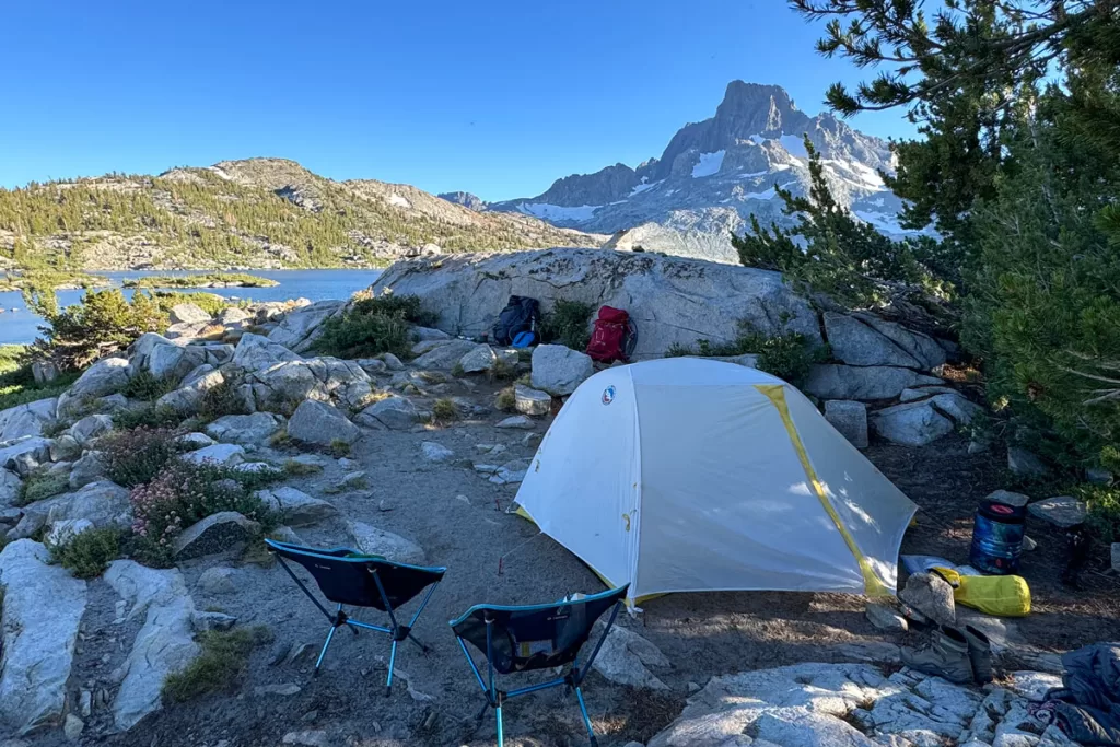 A backpacking campsite sits on a shaded outcropping overlooking Thousand Island Lake in California's eastern Sierra. This post includes everything you need for a backpacking packing list.