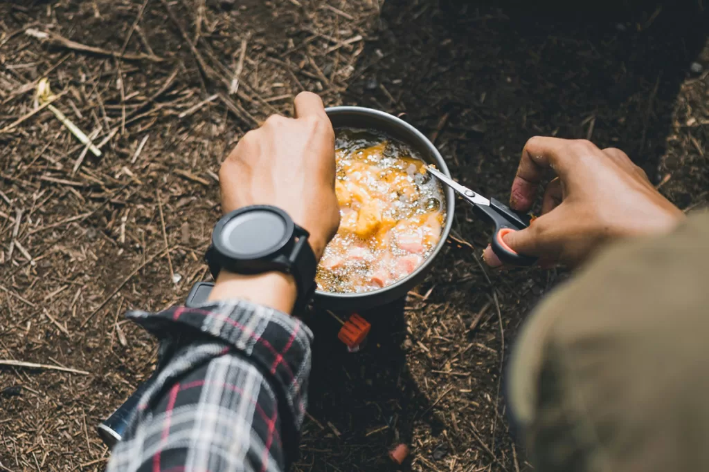 Close-up of a person stirring food in a JetBoil camping stove.