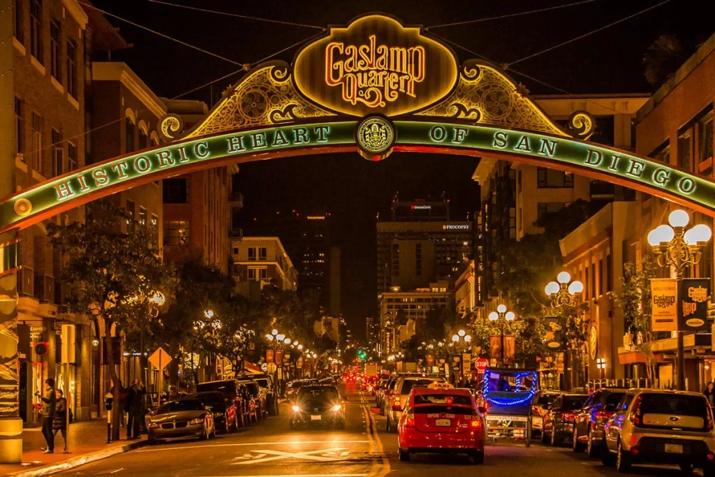 The historic Gaslamp Quarter sign lights up a nighttime street in downtown San Diego, California.