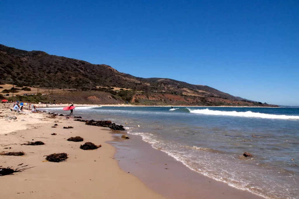 A surfer walks towards waters edge at Leo Carillo State Beach in Malibu, California.