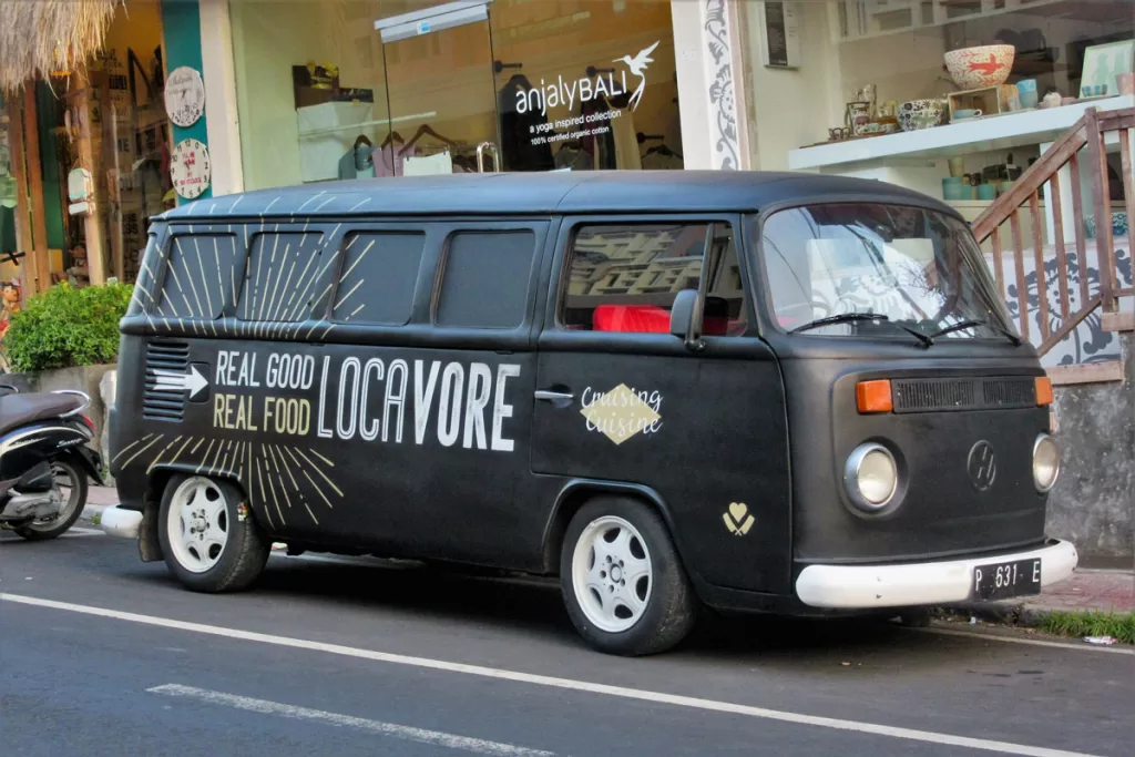 A vintage VW bus, branded with local restaurant Locavore, sits on a street in Ubud, Bali, Indonesia.