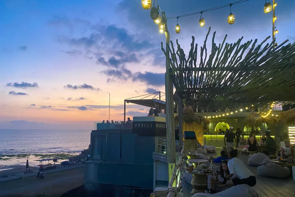 Patrons sit at low tables under strung lights at Sol Rooftop bar in Canggu, Bali.