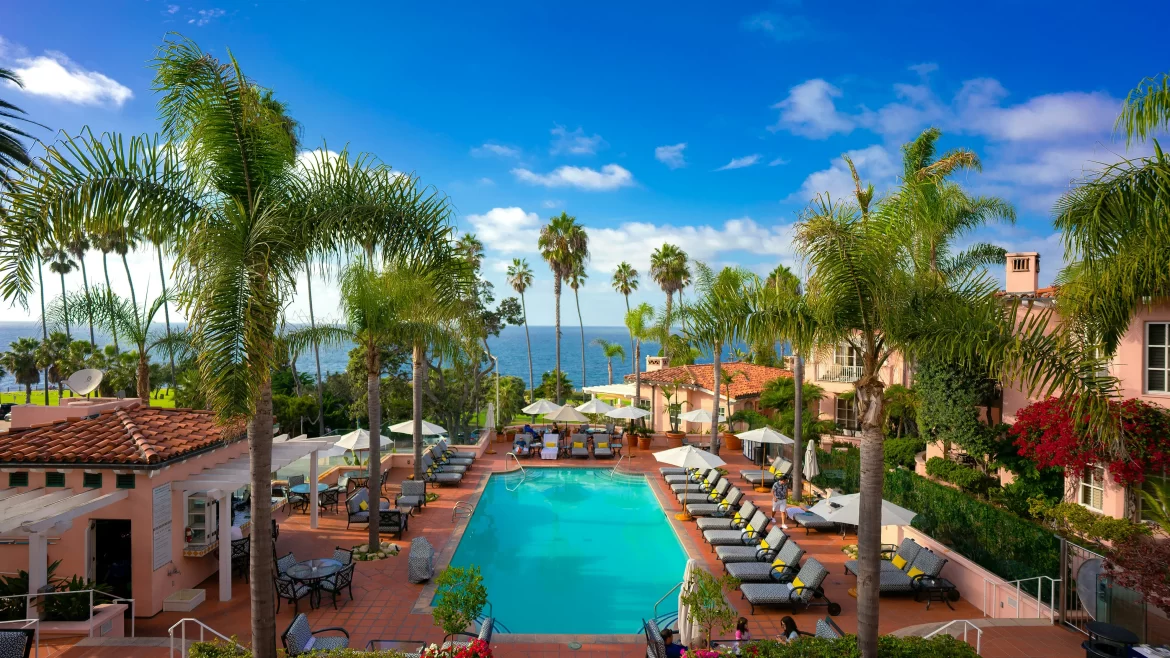 Palm trees line the pool at the Valencia Hotel in La Jolla, California, with views of the Pacific Ocean beyond.